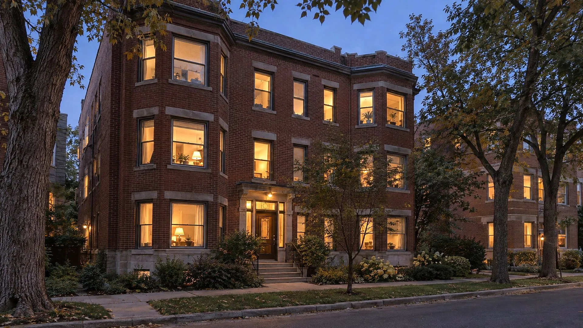 A brick apartment building at dusk with lit windows